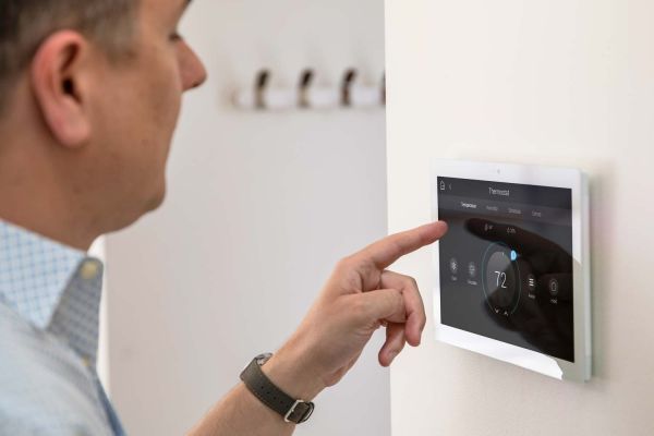 Homeowner adjusting a Control4 thermostat on a wall touch panel