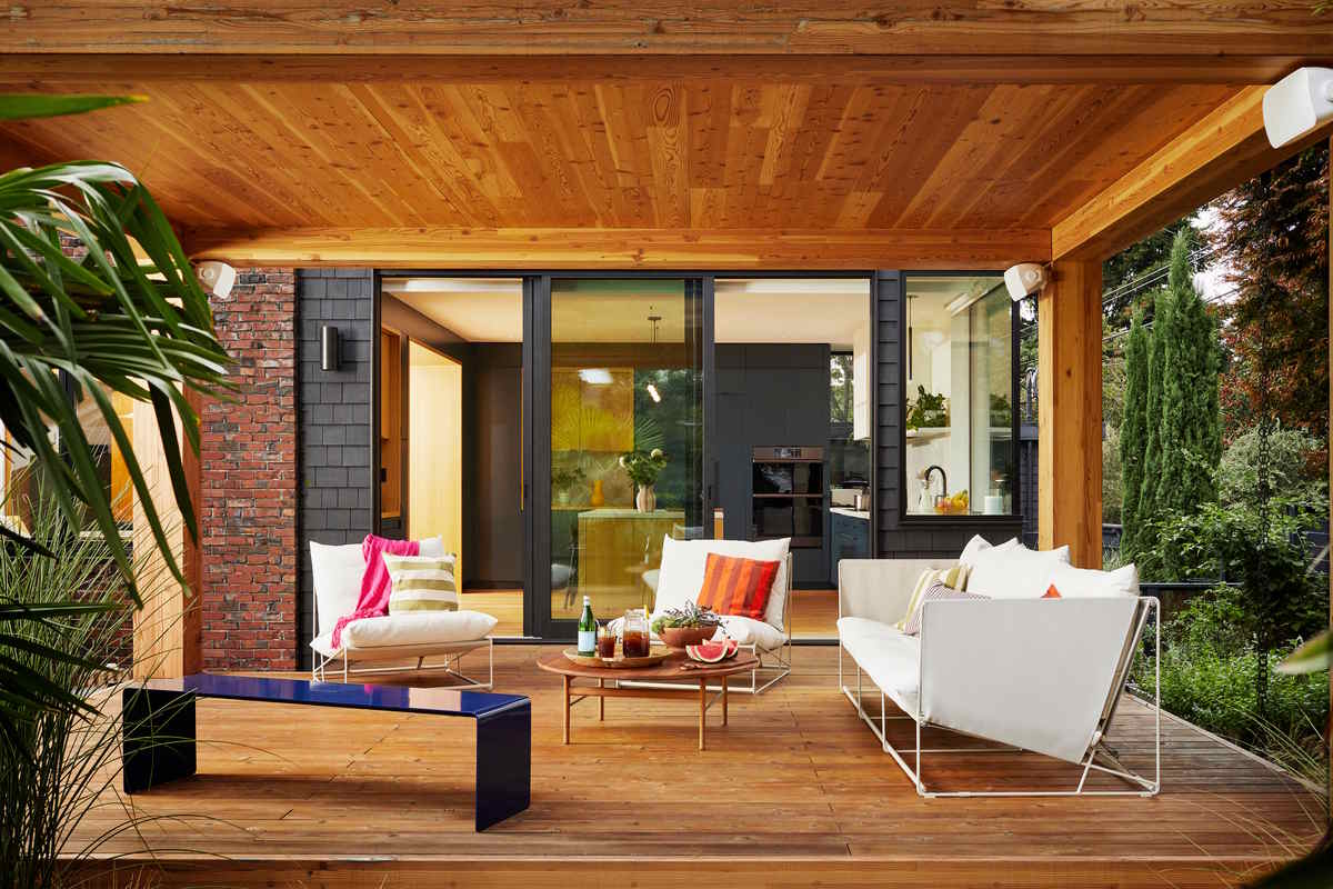 Modern outdoor patio with wooden deck, lounge chairs, and sliding doors opening to the kitchen.