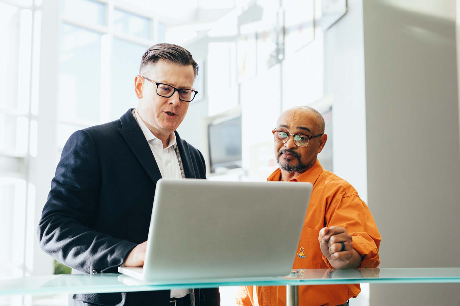 two men discussing information on a laptop alone