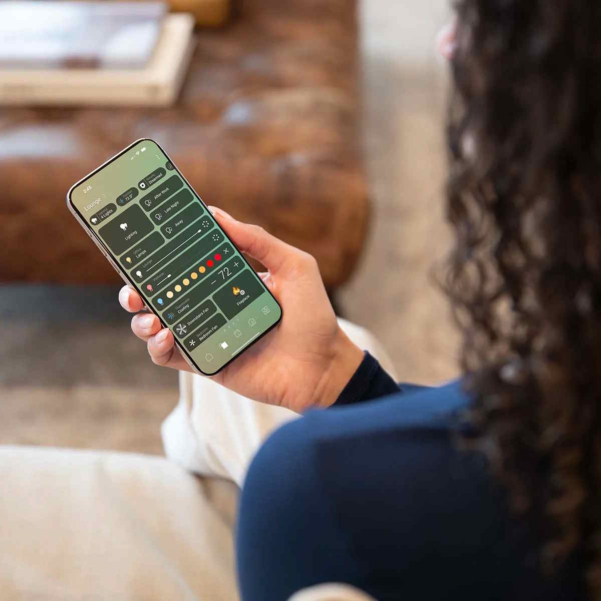 Person holding a smartphone showing a smart‑home control interface.