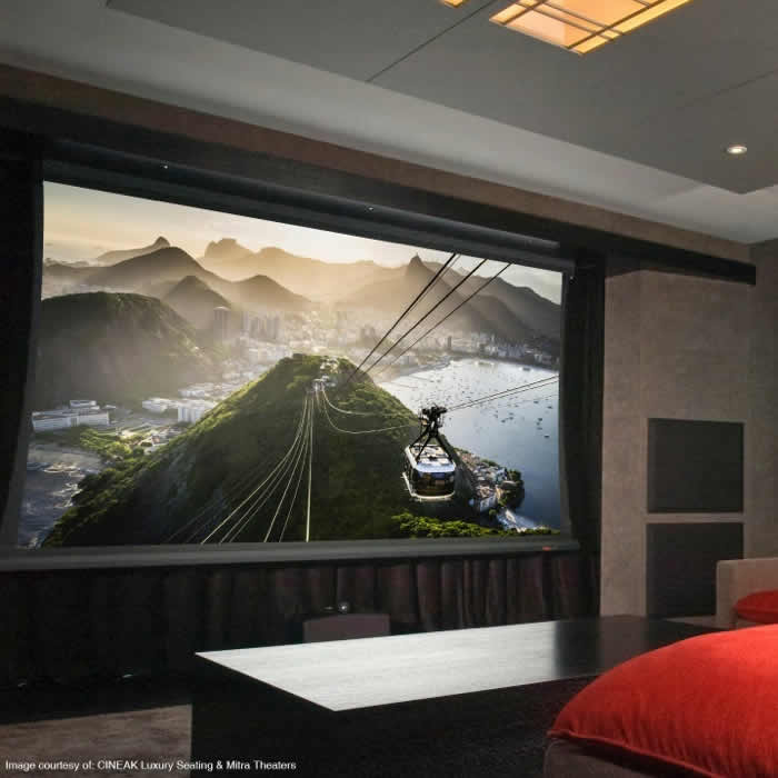 A home theater projection screen displaying a scenic mountain and cable car landscape above a sleek black table.