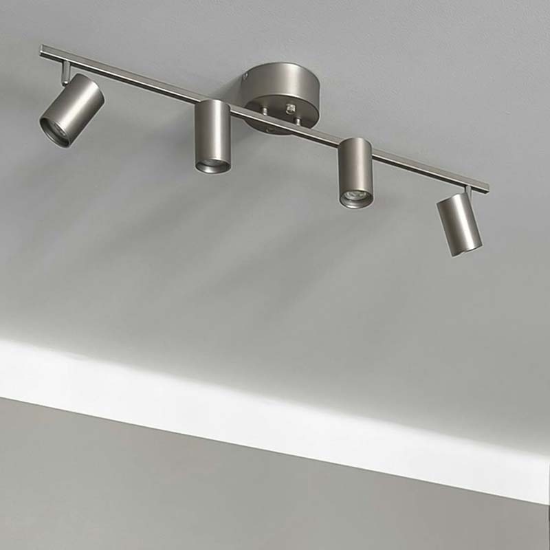A brushed nickel track lighting system with four adjustable heads, mounted on a white ceiling.