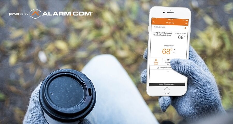 A person viewing their home security system’s interface via an Alarm.com app on their smartphone.