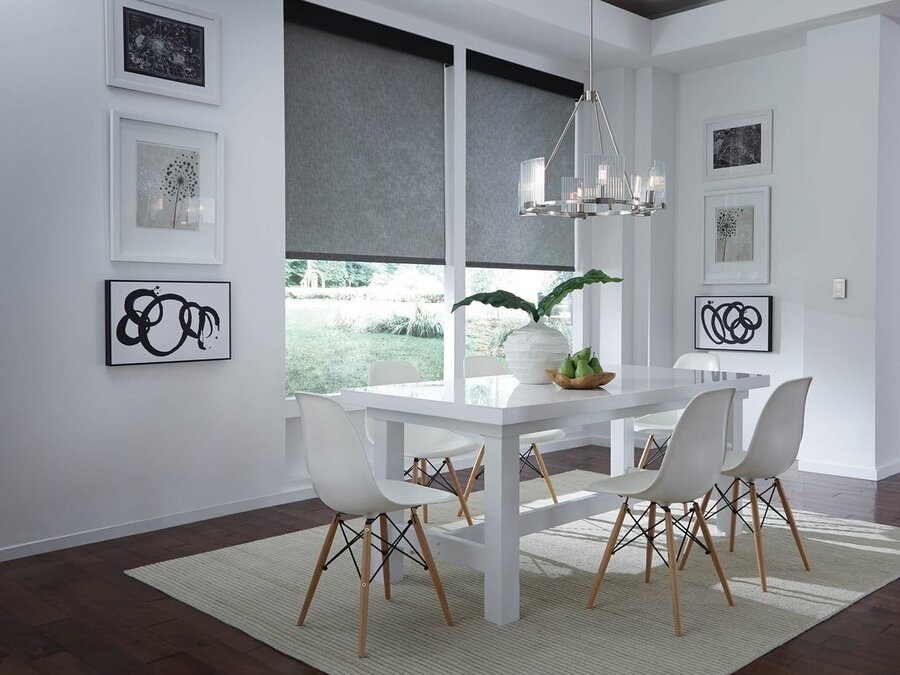 A dining room space featuring motorized shades lowered halfway.