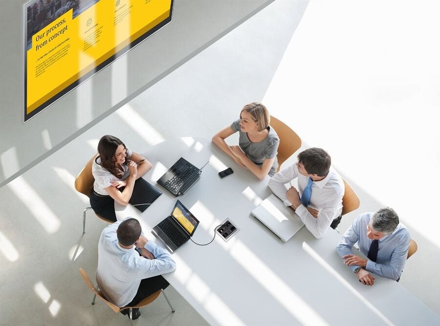 A team around a table in a conference room utilizing Crestron commercial AV solutions.