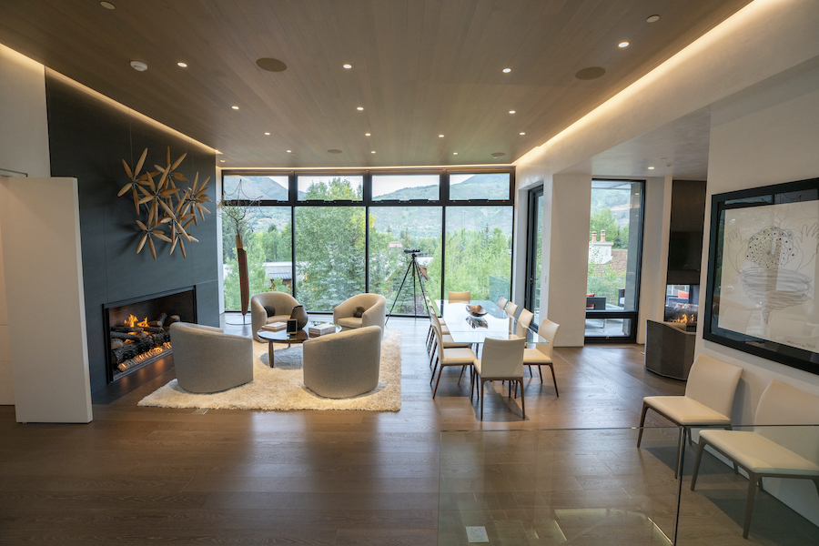 open concept seating and dining space with plush white chairs in front of a fireplace