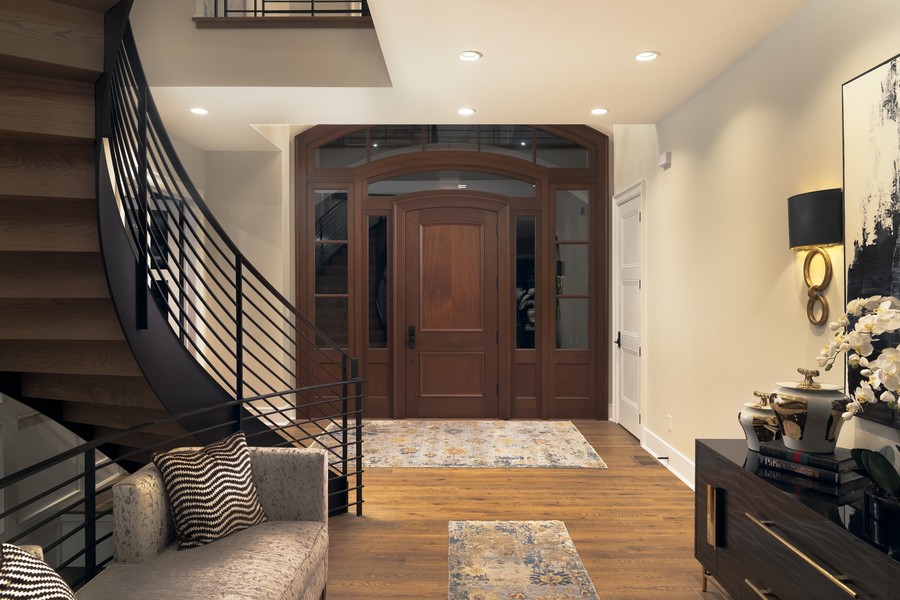 An entryway and staircase illuminated by in-ceiling lights. 