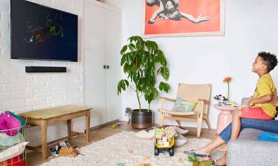 child sitting on a parent’s lap while watching a TV mounted to the wall in a playroom.