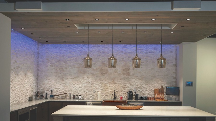 four pendant lights above a kitchen island with blue ceiling illumination
