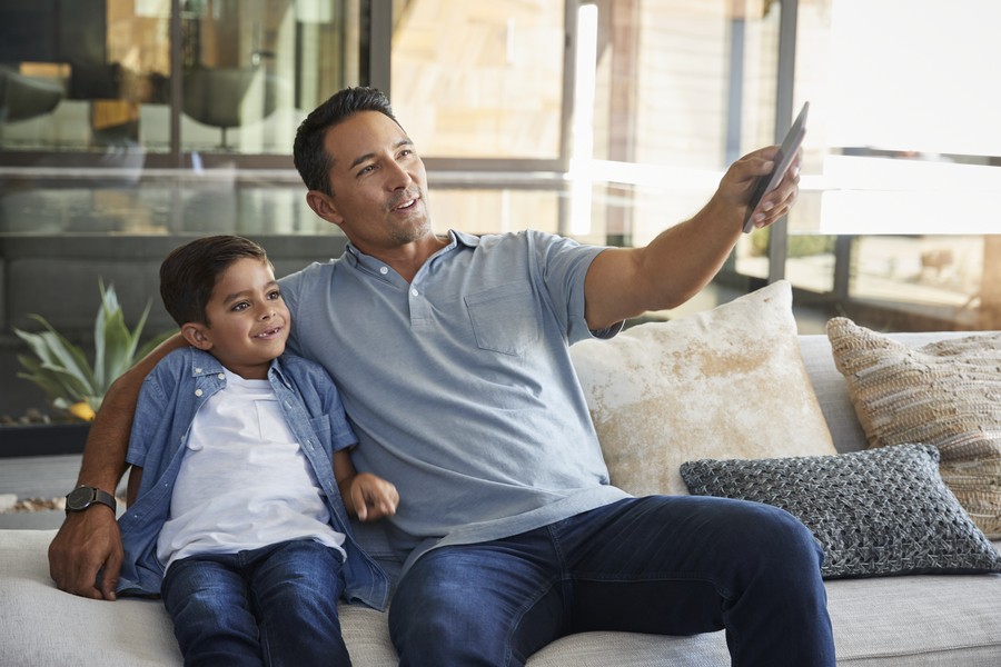 A father and a son watching TV in their smart home.