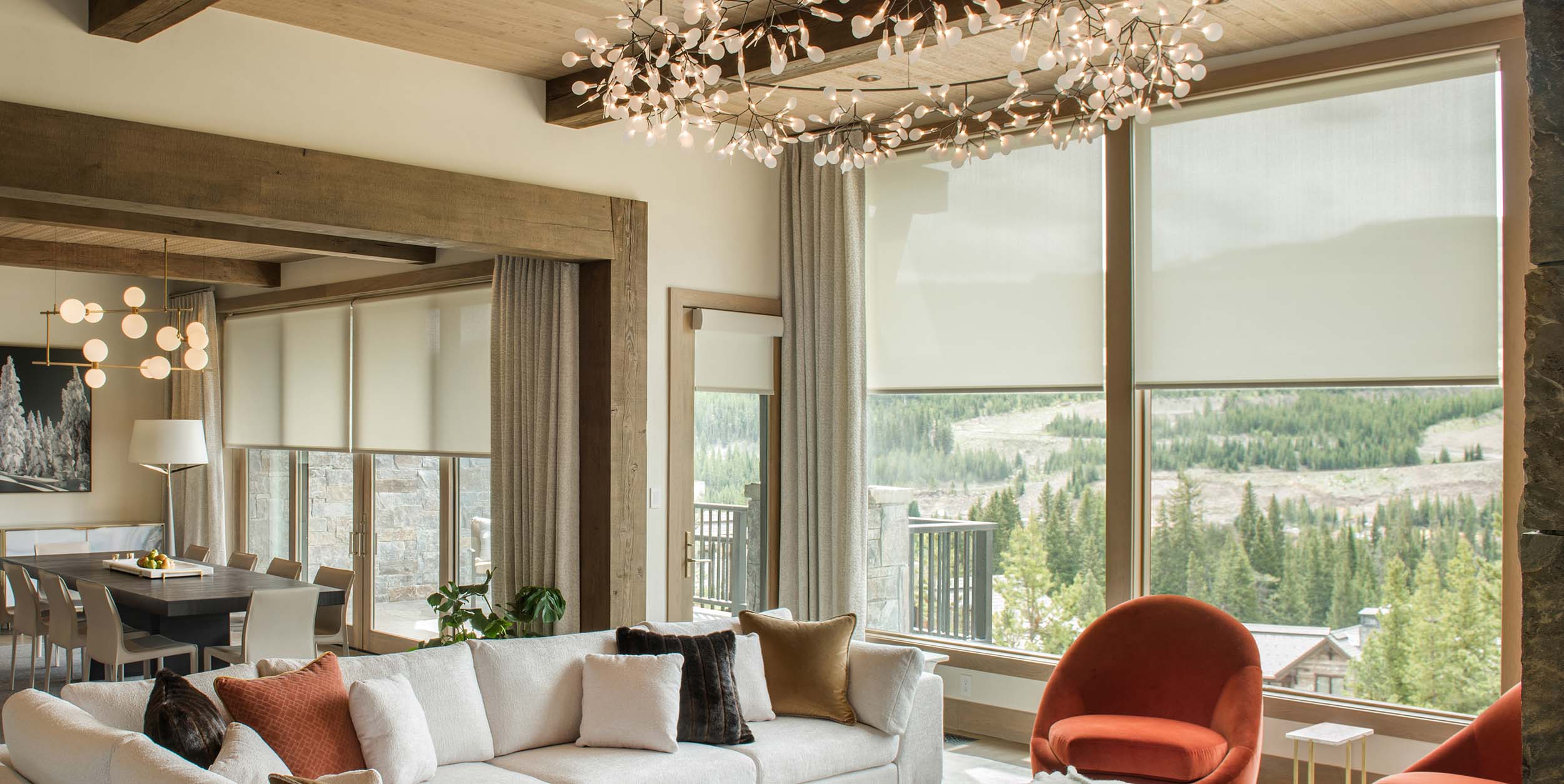 Modern living and dining room with large windows overlooking a mountain landscape.