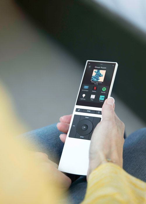 Woman in yellow sweatshirt holding a Neeo remote