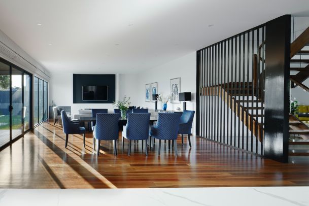 White dining area with table with blue chairs and glass doors