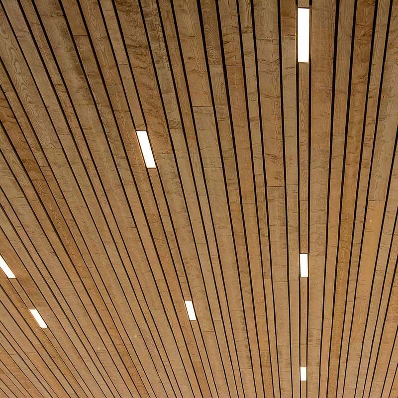 A ceiling composed of parallel wooden slats with slim LED light channels running between them.
